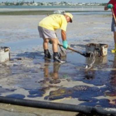 Hombres limpiando derrame de petróleo en la playa Hombres limpiando derrame de petróleo en la playa